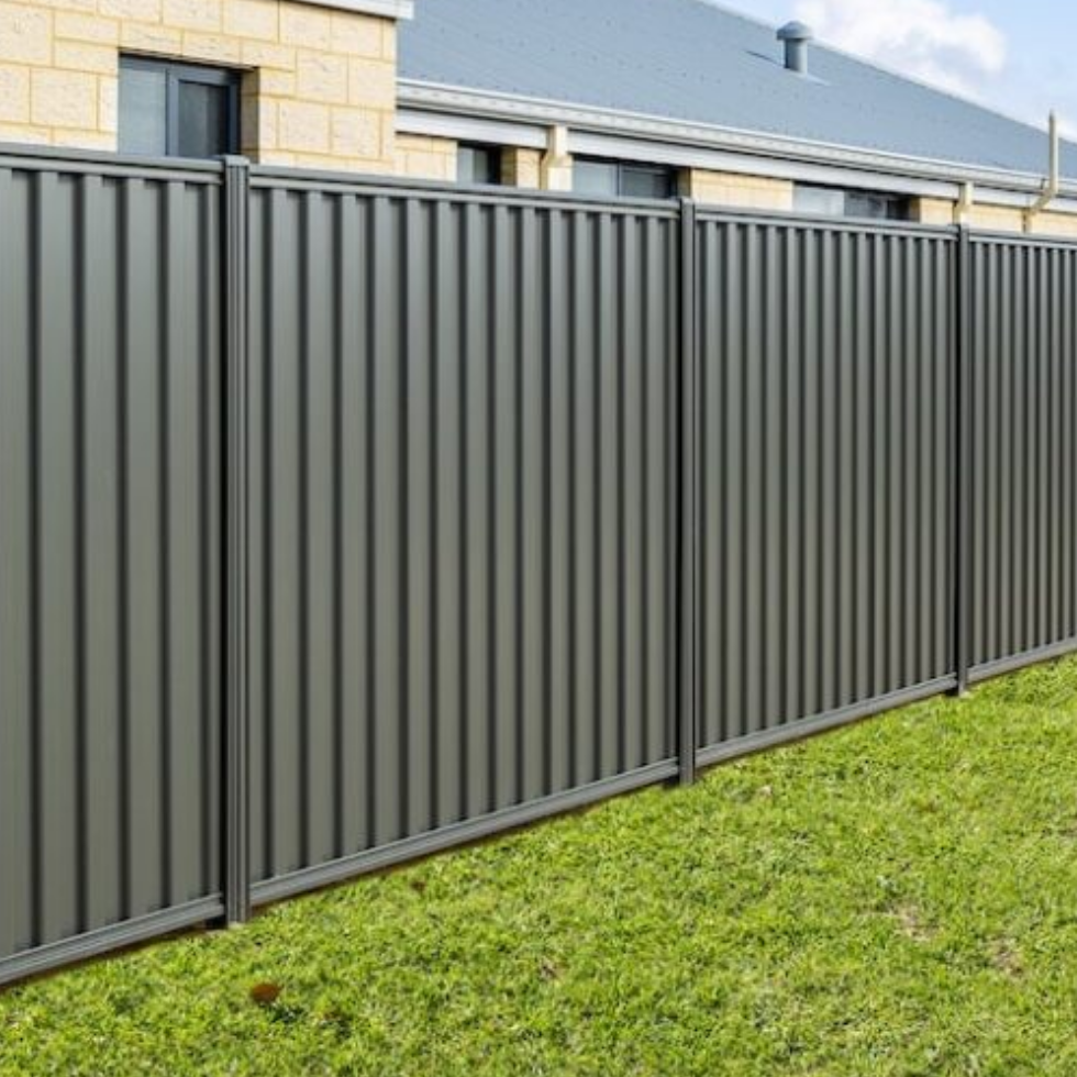 Gray metal fence along a grassy area with houses in the background